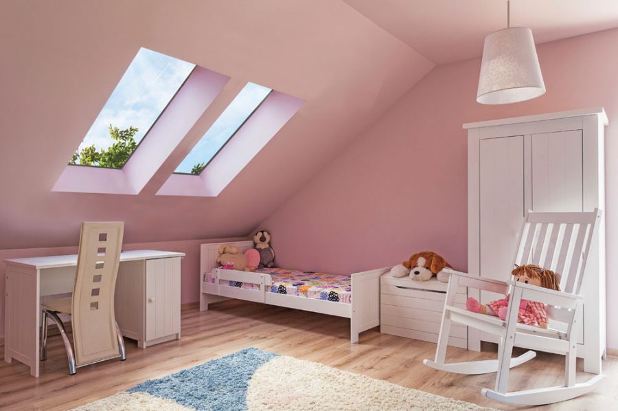 Girls bedroom with pink walls and doll in white rocking chair under two pitched rooflights.